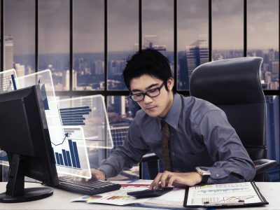 Image of young Asian businessman working with calculator and virtual chart on the computer monitor